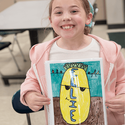 Tackle fundraising with an Art Fundraiser for Schools from Art to Remember image shows girl holding up artwork