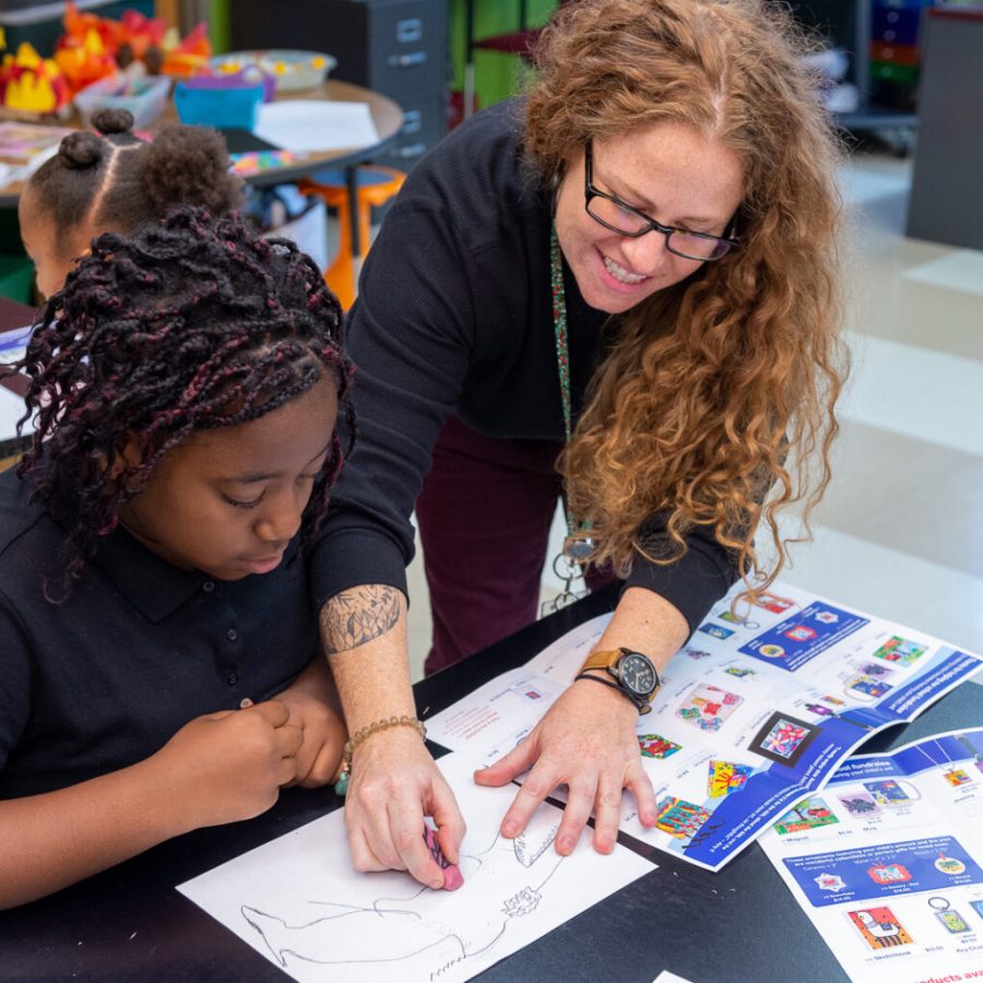 Reach out to Art to Remember about an Art Fundraiser for Schools image shows teacher working with student